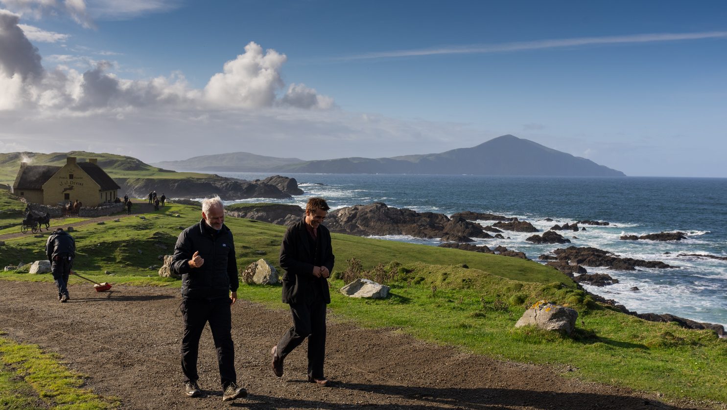 The Banshees of Inisherin: Detrás de cámara, el director Martin McDonagh hablando y caminando con el actor Colin Farrell, mientras un equipo de producción barre el anden en la parte de atrás.